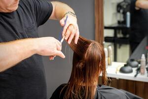 mulher tendo uma Novo corte de cabelo. masculino estilista de cabelo corte Castanho cabelo com tesouras dentro uma cabelo salão. foto