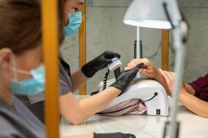 dois mulheres obtendo uma manicure tratamento dentro beleza salão. foto