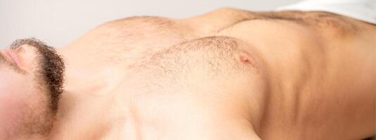 peludo corpo, estômago, e peito do uma homem deitado antes depilação. foto