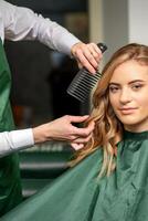 cabeleireiro fazer estilo de cabelo para a mulher enquanto pentear com escova de cabelo, pente dentro uma cabelo salão. foto