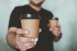 homem alcançando Fora uma Castanho quente café copo do café dando você. masculino trazendo café foto