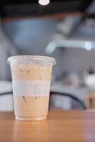 gelado café com leite café dentro plástico Leve embora vidro em madeira mesa foto
