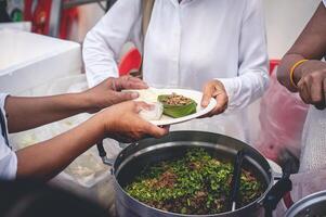 sem teto pessoas alcance Fora para receber livre Comida este voluntários trazer. para Socorro aliviar fome foto