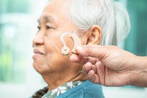 ásia Senior mulher paciente vestindo uma audição ajuda para tratando audição perda problema. foto