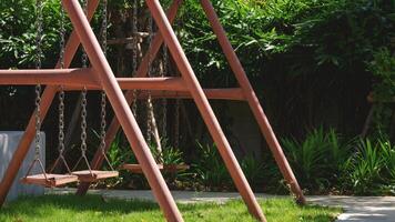 a velho metal balanço com muitos verde plantar dentro jardinagem área às público parque, lado Visão com cópia de espaço foto