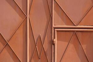 fundo e textura do a velho laranja metal portão porta do máquina oficina com geométrico linhas padronizar em superfície foto