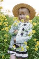 Loiras menina dentro uma campo com amarelo flores uma menina dentro uma Palha chapéu é colheita flores dentro uma campo. uma campo com colza. foto