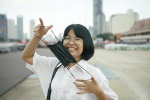 adolescente asiático alegre com máscara de proteção na mão foto