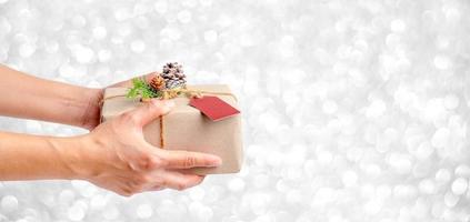 feche a mão de uma mulher segurando uma caixa de presente de natal foto
