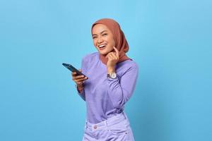 retrato de uma jovem asiática sorridente, usando um telefone celular sobre fundo azul foto