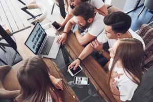 um grupo de jovens com gadgets e um laptop organizam um brainstorm e se comunicam entre si. o conceito de desenvolver um jovem negócio foto