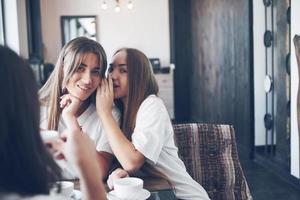 as três melhores amigas se reuniram para beber café e fofocar. garotas se divertindo e rindo foto