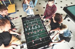 jovens sorridentes jogando futebol de mesa dentro de casa foto