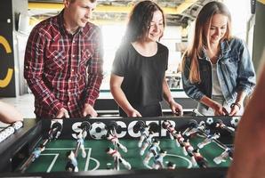 jovens sorridentes jogando futebol de mesa dentro de casa foto