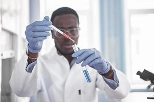 um trabalhador afro-americano trabalha em um laboratório conduzindo experimentos. foto