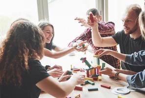 um grupo de amigos criativos sentado em uma mesa de madeira. as pessoas se divertiam jogando um jogo de tabuleiro. foto