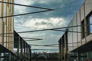 moderno arquitetura com geométrico metal estruturas contra uma dramático nublado céu, exibindo contemporâneo urbano Projeto e aberto espaços. foto