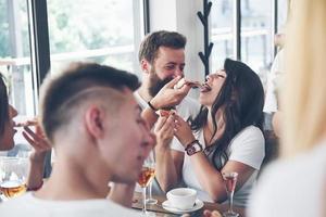 pizza saborosa na mesa, com um grupo de jovens sorridentes descansando no bar foto