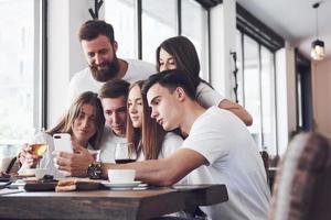 um grupo de pessoas tira uma foto de selfie em um café. os melhores amigos reunidos em uma mesa de jantar comendo pizza e cantando vários drinks