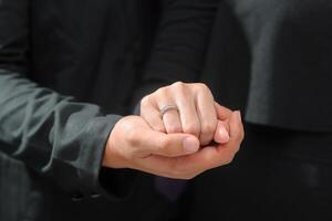 Casamento anel foto tiro conceito uma homem vestindo uma formal Preto terno e roxa gravata é segurando uma Casamento anel