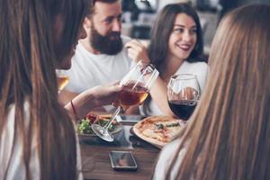 amigos se reuniram à mesa com comida deliciosa com taças de vinho tinto para comemorar uma ocasião especial foto