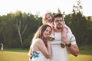 família feliz, pai de mãe e filha de bebê na natureza ao pôr do sol foto