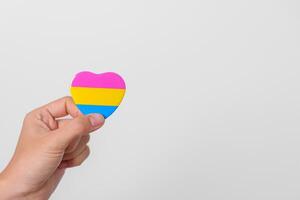 pansexual orgulho dia e lgbt orgulho mês conceito. mão segurando rosa, amarelo e azul coração forma para lésbica, gay, bissexual, transgênero, queer e pansexual comunidade foto