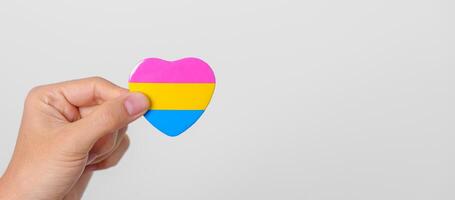 pansexual orgulho dia e lgbt orgulho mês conceito. mão segurando rosa, amarelo e azul coração forma para lésbica, gay, bissexual, transgênero, queer e pansexual comunidade foto