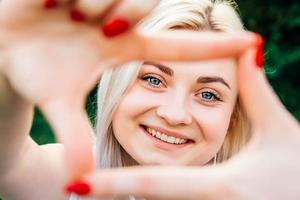 mulher sorrindo fazendo moldura com as mãos e os dedos foto