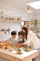 momentos felizes em família quando os filhos ajudam a mãe a preparar comida na cozinha. foto