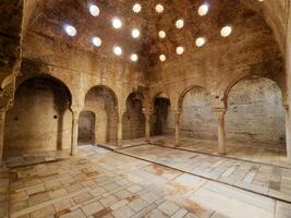 vista interior dos banhos árabes el banuelo, em granada espanha. luz do sol entrando no teto. interior antigo e histórico de banhos árabes. arquitetura mourisca. foto