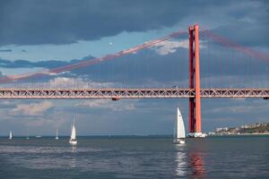 barcos Navegando em a tagus rio dentro Lisboa, Portugal. 25 abril ponte dentro a fundo. foto