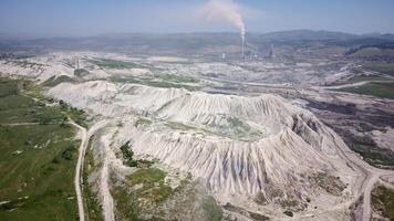 vista aérea do poço da mina de trabalho. tiro de drone da atividade de mineração de carvão. lagos artificiais poluídos. montanhas com neve ao fundo. Extração. máquina funcionando. paisagem destruída. foto