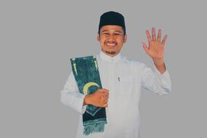 muçulmano homem caminhando e acenando mão para cumprimentar alguém com feliz expressão foto