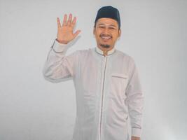 muçulmano ásia homem mostrando feliz expressão quando acenando mão para cumprimentar alguém foto