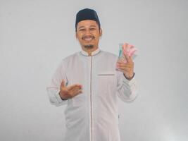 ásia muçulmano homem segurando dinheiro com grato gesto foto