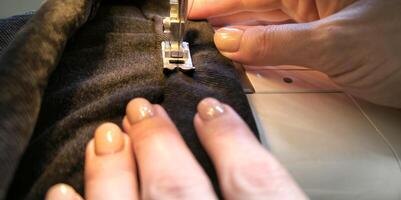 processo do de costura dentro uma de costura máquina costurar mulher mãos manicure Preto têxtil jeans jeans fabricação fechar acima costureira dentro oficina tecido roupas fazer Projeto passatempo feito à mão trabalhando bordado foto