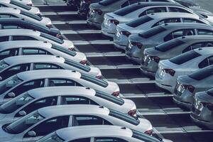 linhas do uma Novo carros estacionado dentro uma distribuição Centro em uma carro fábrica em uma ensolarado dia. topo Visão para a estacionamento. foto