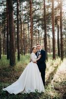 a noiva e o noivo estão caminhando em uma floresta de pinheiros foto