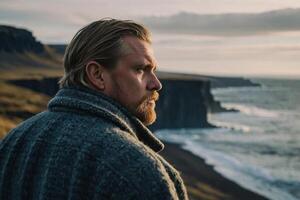 uma homem com uma barba e uma suéter em pé perto a oceano foto