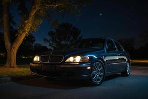 uma carro estacionado às noite dentro frente do uma árvore foto