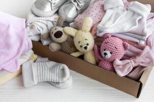 bebê roupas, tricotado brinquedos, meias e sapatos dentro caixa. foto