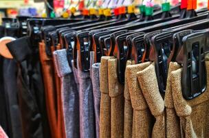 linhas do calças dentro uma roupas loja suspensão ordenadamente em cabides. foto