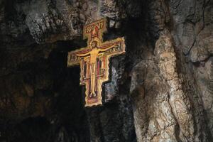 antigo crucifixo suspensão a partir de a topo do uma caverna foto