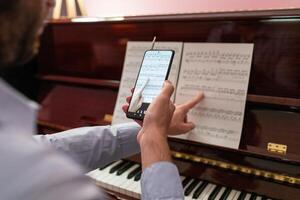 homem fazer controlo remoto música piano lição com Smartphone transmissão foto