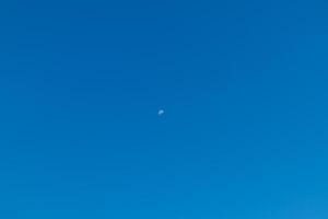 Claro azul céu com metade lua foto