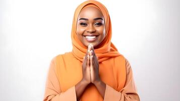 africano mulher vestindo cachecol é Rezar e sorridente em cinzento fundo foto