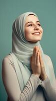 europeu mulher vestindo cachecol é Rezar e sorridente em verde fundo foto