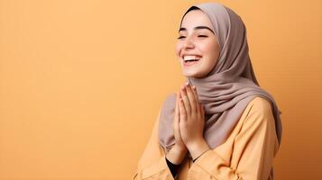 europeu mulher vestindo cachecol é Rezar e sorridente em laranja fundo foto