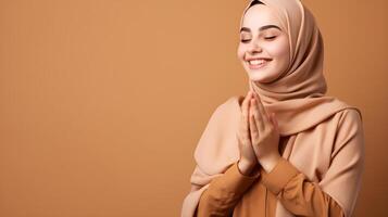 árabe mulher vestindo cachecol é Rezar e sorridente em Castanho fundo foto